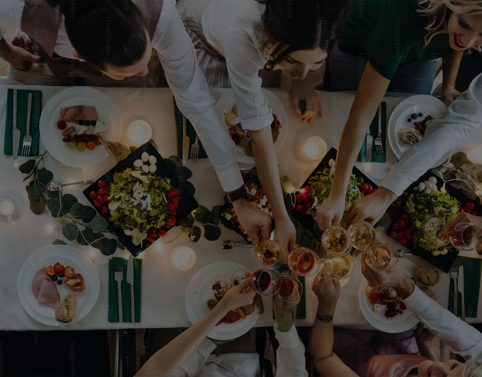 Overhead view of a dinner table with people clinking glasses